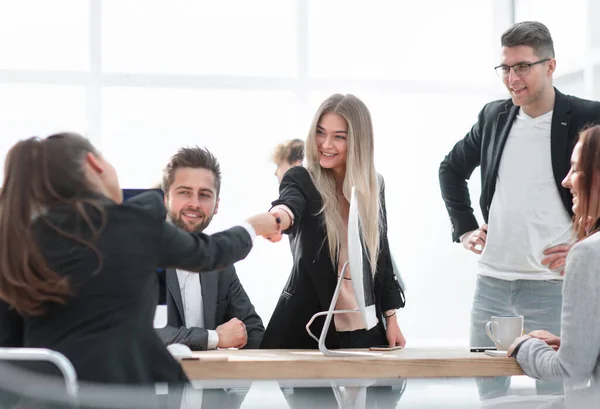 Dos mujeres jóvenes estrechando las manos cerca de una oficina Escritorio. — Foto de Stock