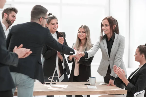 Twee jonge vrouwen schudden handen in de buurt van een bureau. — Stockfoto