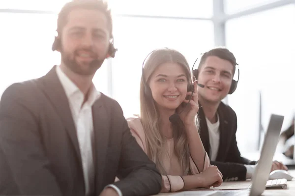 Werknemers in een headset zittend aan een bureau. — Stockfoto