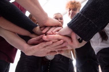 Bir grup farklı genç insan ellerinden bir kule yapıyorlar.