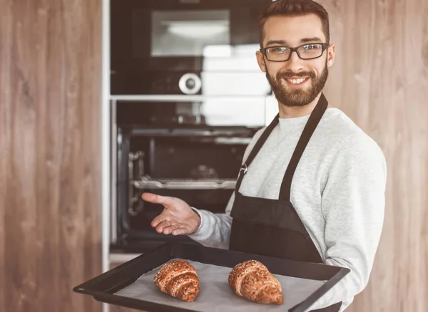 Smiling man holding a tray of fresh croissants — Stock Photo, Image