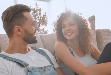 Yeni evliler yeni bir dairede kanepede oturuyor..