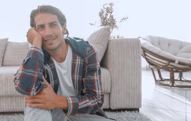 Kendine güvenen adam rahat bir oturma odasında halı üzerinde oturan.