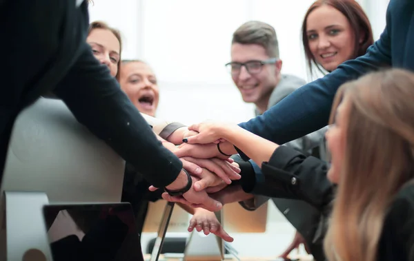 Grupo de empleados que forman una pila de manos en el escritorio — Foto de Stock