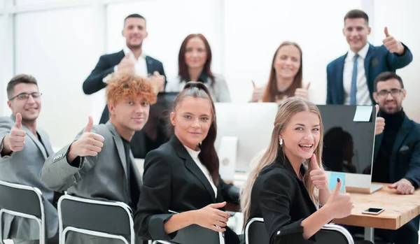 På nära håll. leende affärsteam sitter vid ett skrivbord. — Stockfoto