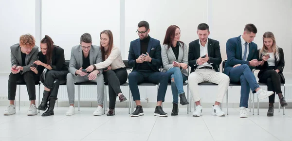 Groep van diverse jonge zakenmensen op zoek naar hun smartphone schermen. — Stockfoto