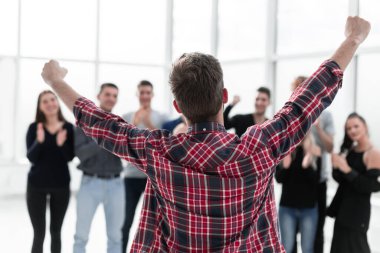 Genç girişimci alkışlayan iş adamlarının önünde duruyor.