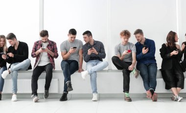 Sıraya dizilmiş akıllı telefonları olan bir grup sıradan genç..