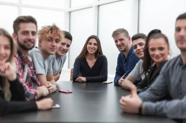 Equipo de jóvenes profesionales sentados en una mesa en una sala de conferencias . — Foto de Stock