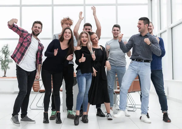 Team av glada ungdomar som står på ett nytt kontor — Stockfoto