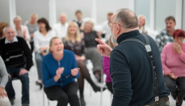 Olgun beyaz adam modern açık ofiste bir konuşma yapıyor.