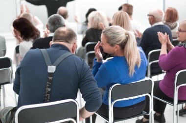 Yetişkin izleyiciler konuşmacının konuşmasını dinliyor.