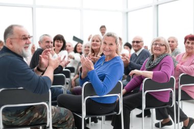 Yetişkin insanlar öğretim üyelerinin motivasyon konuşmalarını dinlerler.