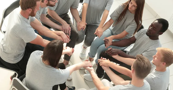 young people holding each others hands at a group meeting.