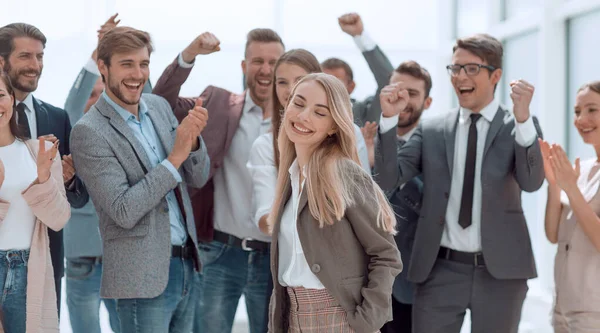 Heureuse jeune femme debout devant ses collègues jubilants — Photo