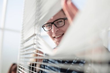 Genç düşünceli işadamı ofiste pencereden dışarı bakıyor.