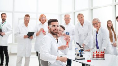 gülümseyen bilim adamı laboratuvar masasında oturuyor. .
