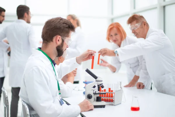 De cerca. joven científico sentado en una mesa en el laboratorio. — Foto de Stock