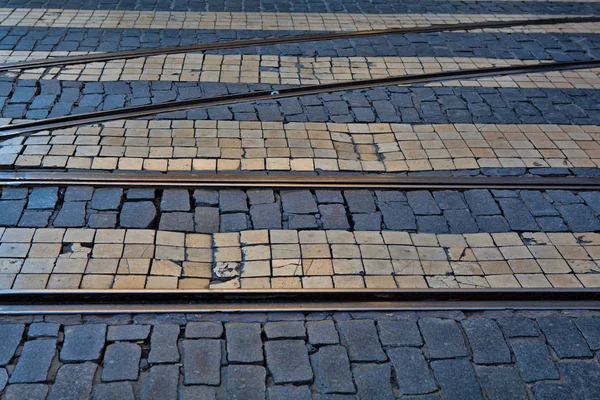 Старые железнодорожные линии на мощеной поверхности дороги — стоковое фото