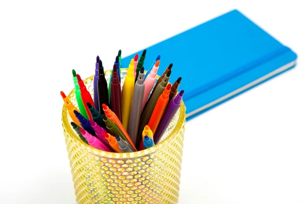 Defter ve beyaz bir arka plan üzerinde renkli işaretleyicileri