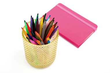 Defter ve beyaz bir arka plan üzerinde renkli işaretleyicileri