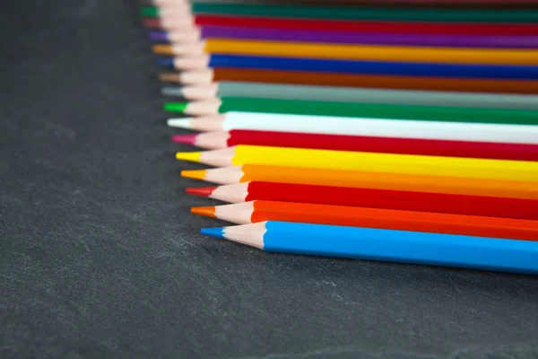 Lápices de colores en una pizarra de piedra negra — Foto de Stock