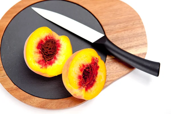 Bıçak ile ahşap kesme tahtası üzerinde taze yıkanmış şeftali