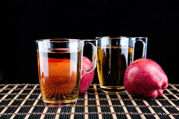Дві склянки соку і яблук на чорному фоні — стокове фото