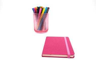 Defter ve beyaz bir arka plan üzerinde renkli işaretleyicileri