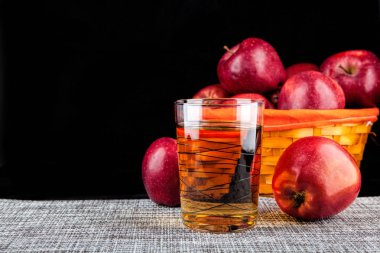 cam suyu ve siyah bir zemin üzerine kırmızı elmalar