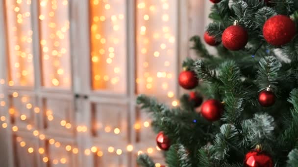 Χριστούγεννα δέντρο με κόκκινα παιχνίδια σχετικά με φόντο τα φώτα — Αρχείο Βίντεο