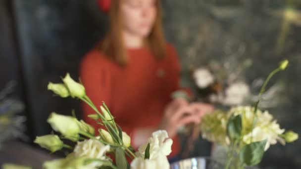 Квіти на розмитому фоні флориста дівчина робить квіткову композицію — стокове відео