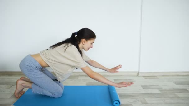 Junge Frau macht Yoga-Übungen - öffnet ihre Yogamatte — Stockvideo