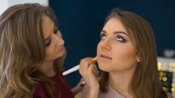 Maquillaje artista hace una chica hermoso maquillaje para la cara antes de un evento importante — Vídeo de stock