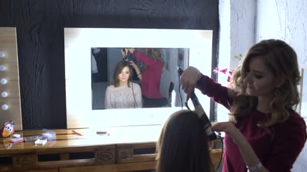 Визажист заставляет красивую девушку прическу отражать зеркало макияжа — стоковое видео