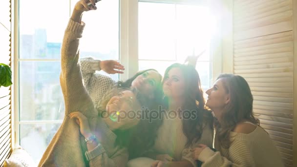 Vier schöne Mädchen schießen Selfie am Fenster sitzend. Freundinnen haben Spaß und lachen im Schlafzimmer — Stockvideo