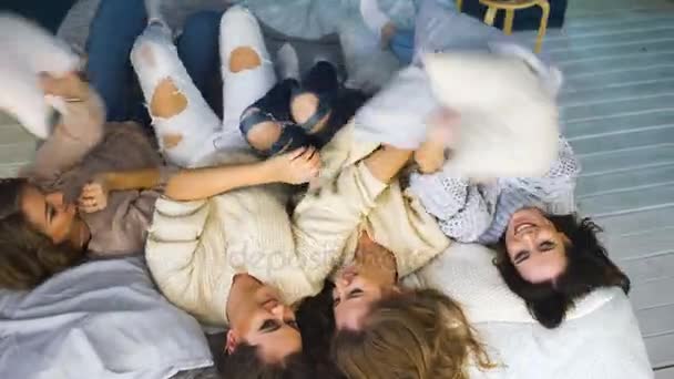 Cuatro hermosas chicas se tiran almohadas. Novias divirtiéndose y riendo en el dormitorio — Vídeos de Stock