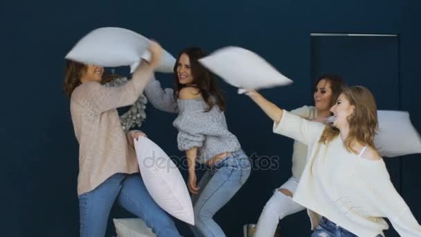 Четыре красивые девушки дерутся подушки друг с другом на кровати медленное движение — стоковое видео