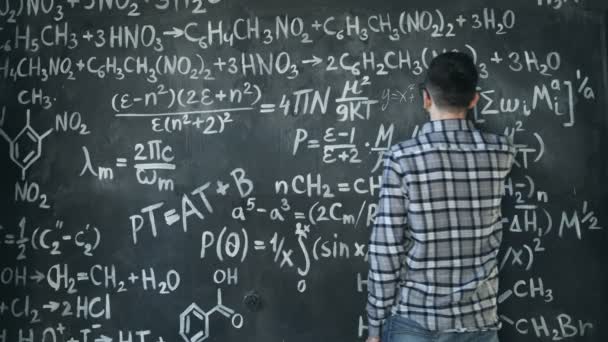 Jovem cientista homem escrever chock em equações químicas e matemáticas parede quarto interior — Vídeo de Stock