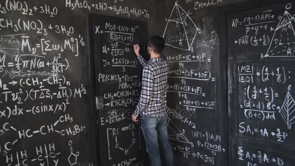 Νεαρό επιστήμονα άνθρωπο γράφουν ασφυκτικά στα χημικά και μαθηματικές εξισώσεις τοίχο δωμάτιο εσωτερικό timelapse — Αρχείο Βίντεο
