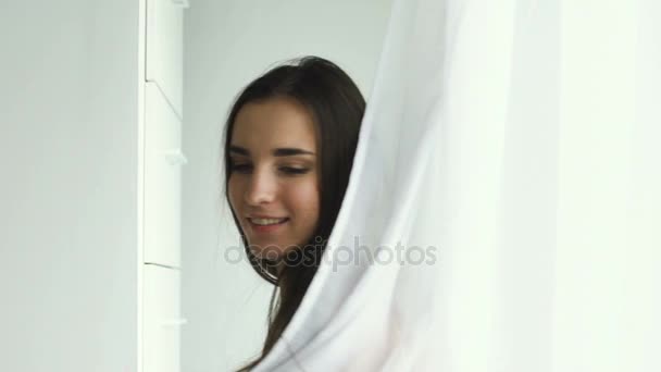 Slowmotion vacker sexig tjej ställer in kameran och smililng nära fönster — Stockvideo