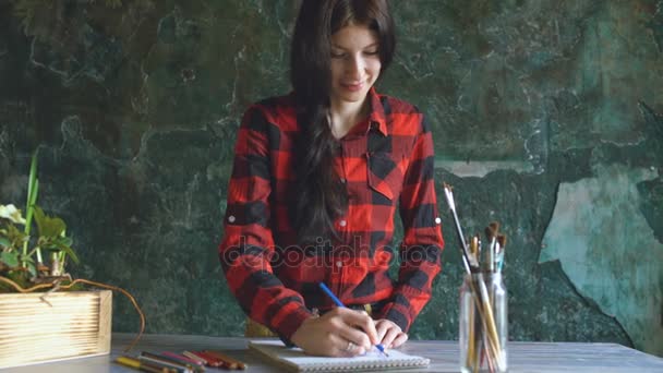 Young woman artist painting scetch on paper notebook with pencil and smile — Stock Video