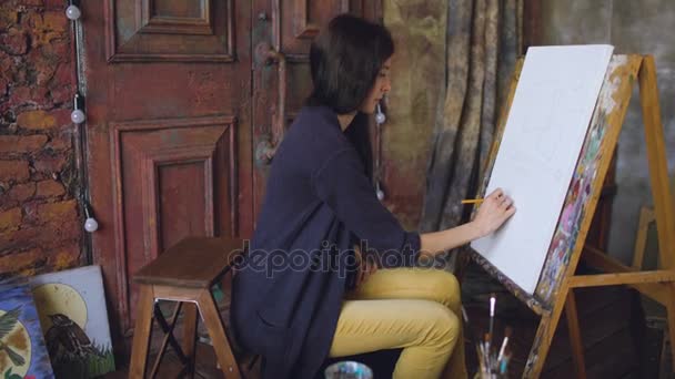 Jovem artista desenha lápis scetch wit sobre tela cavalete, preparando-se para pintar quadro — Vídeo de Stock