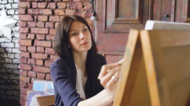 Genç kadın sanatçı pictrure suluboya boya ile çizmek ve şövale tuval üzerine fırça