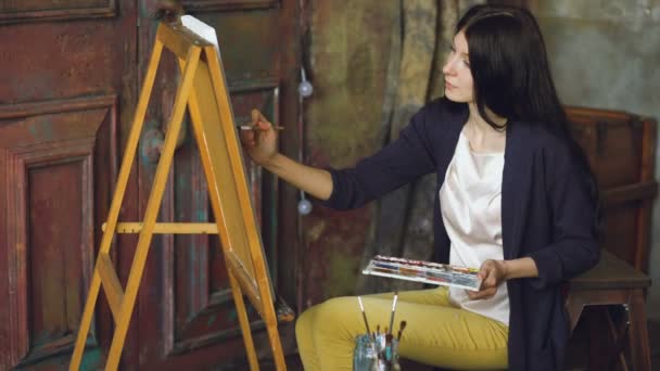 Ung kvinna konstnären Rita pictrure med akvarell färger och borsta på staffli duk — Stockvideo