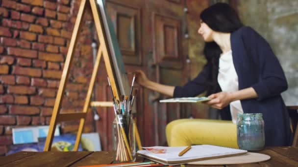 Jovem artista desenhar pictrure com tintas aquarela e escova em tela cavalete — Vídeo de Stock