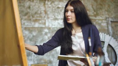 Genç kadın sanatçı pictrure suluboya boya ile çizmek ve şövale tuval üzerine fırça