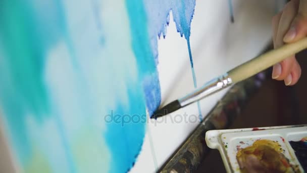 Joven artista dibujar pictrure con pinturas de acuarela y pincel sobre lienzo caballete mano de primer plano — Vídeo de stock