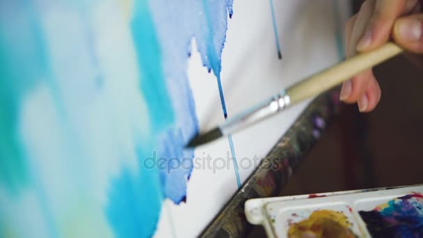 Joven artista dibujar pictrure con pinturas de acuarela y pincel sobre lienzo caballete mano de primer plano — Vídeos de Stock