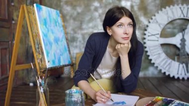 Genç kadın sanatçı pictrure suluboya boya ile çizmek ve loking penceresinde gülümse